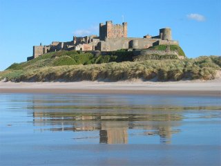 Bamburgh castle during the shore of Northumberland."Bamburgh 2006 closeup" by Michael Hanselmann - Quaoar10. Certified under CC BY-SA 3.0 via Wikimedia Commons.